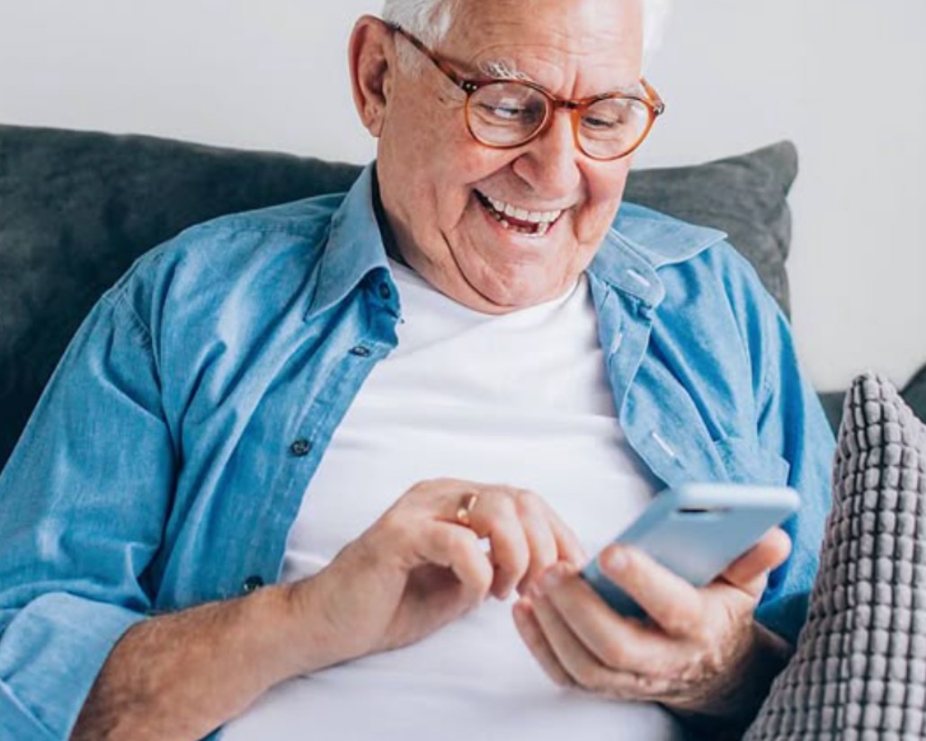 Smiling older man messaging on his phone